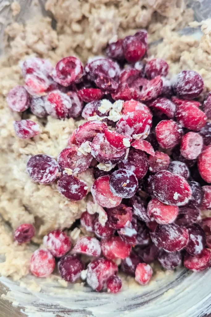 adding the lightly dusted cranberry halves to the oatmeal muffin batter