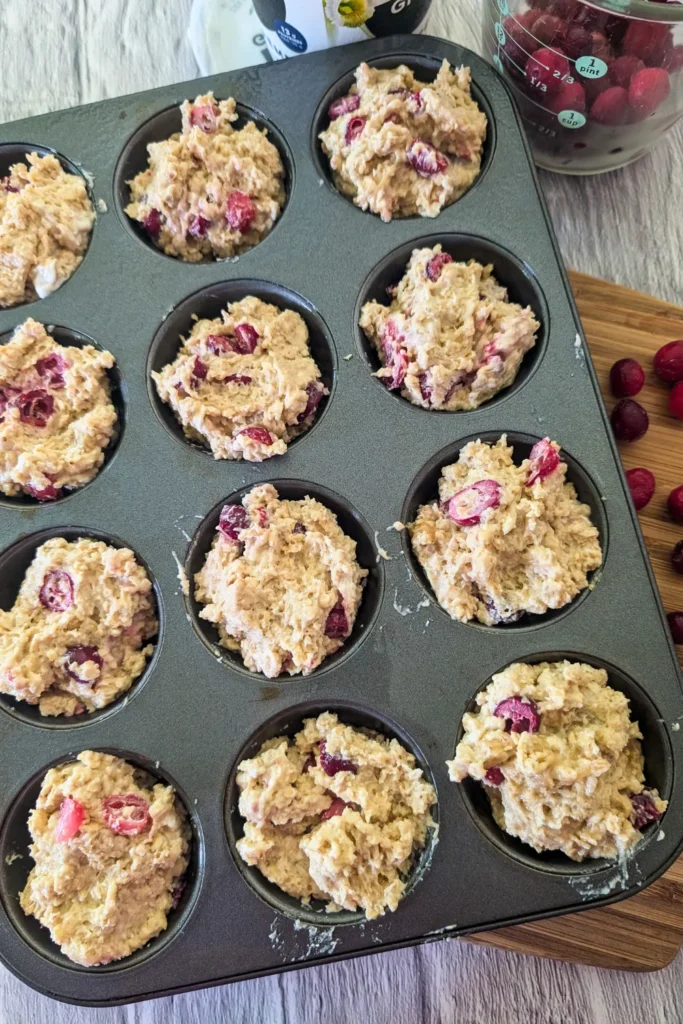 filling the prepared muffin pan with oatmeal cranberry muffin batter