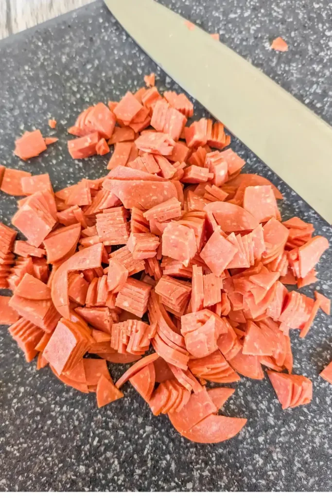diced pepperoni on cutting board with knife