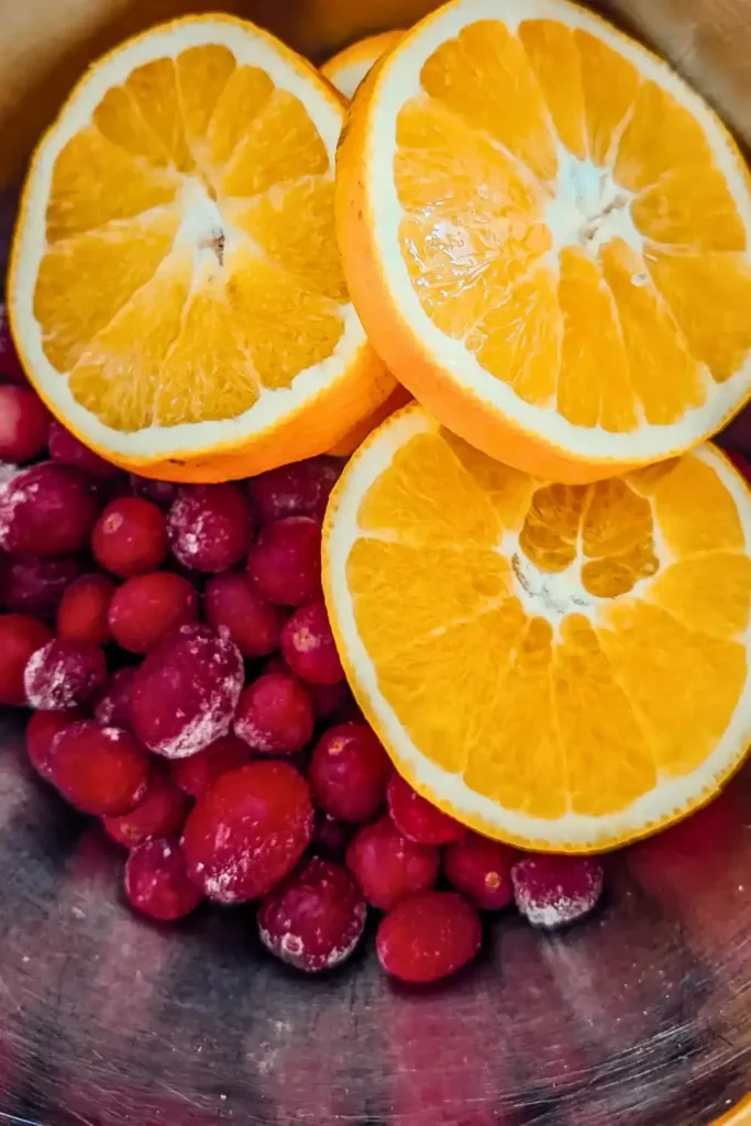 whole cranberries and orange slices in stainless steel bowl