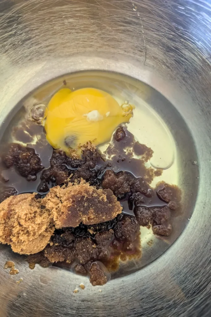 adding large egg to brown sugar and oil