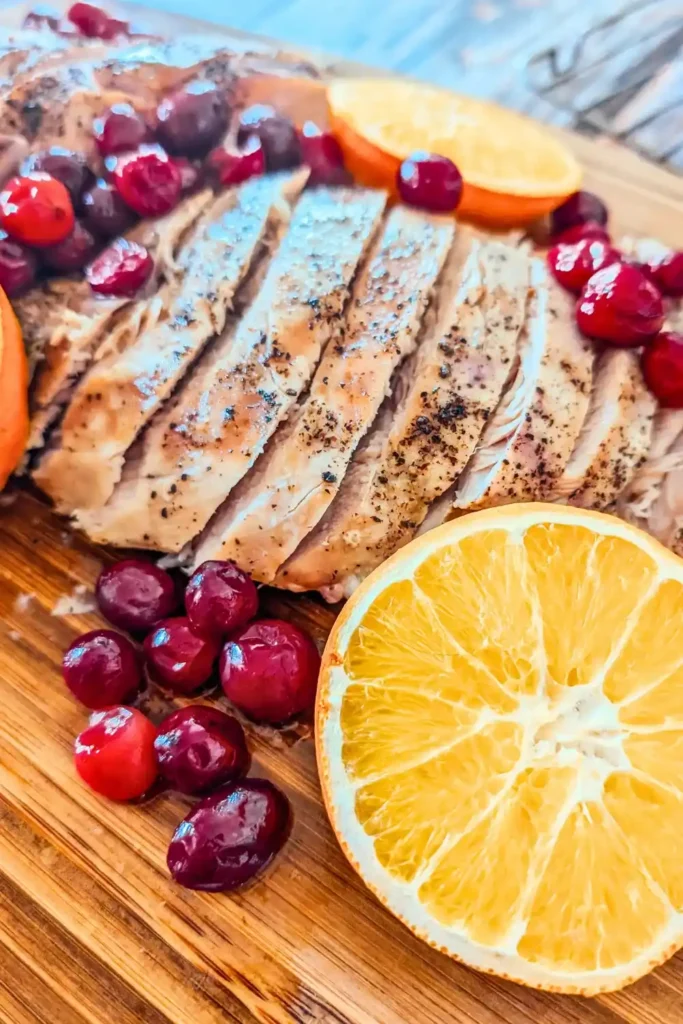 side angle view of cooked turkey breast with cranberries and orange