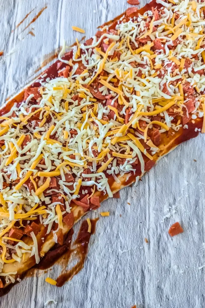 adding mozza-cheddar blend of shredded cheese to pizza
