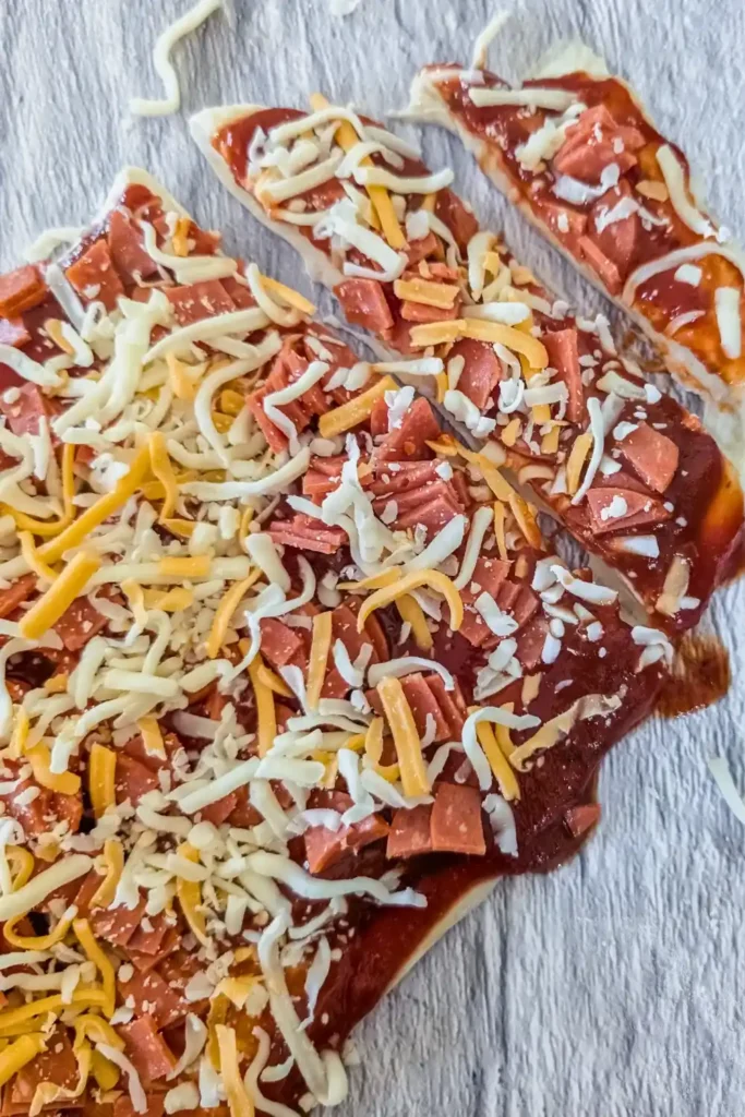 slicing the raw pizza into smaller sections for rolling