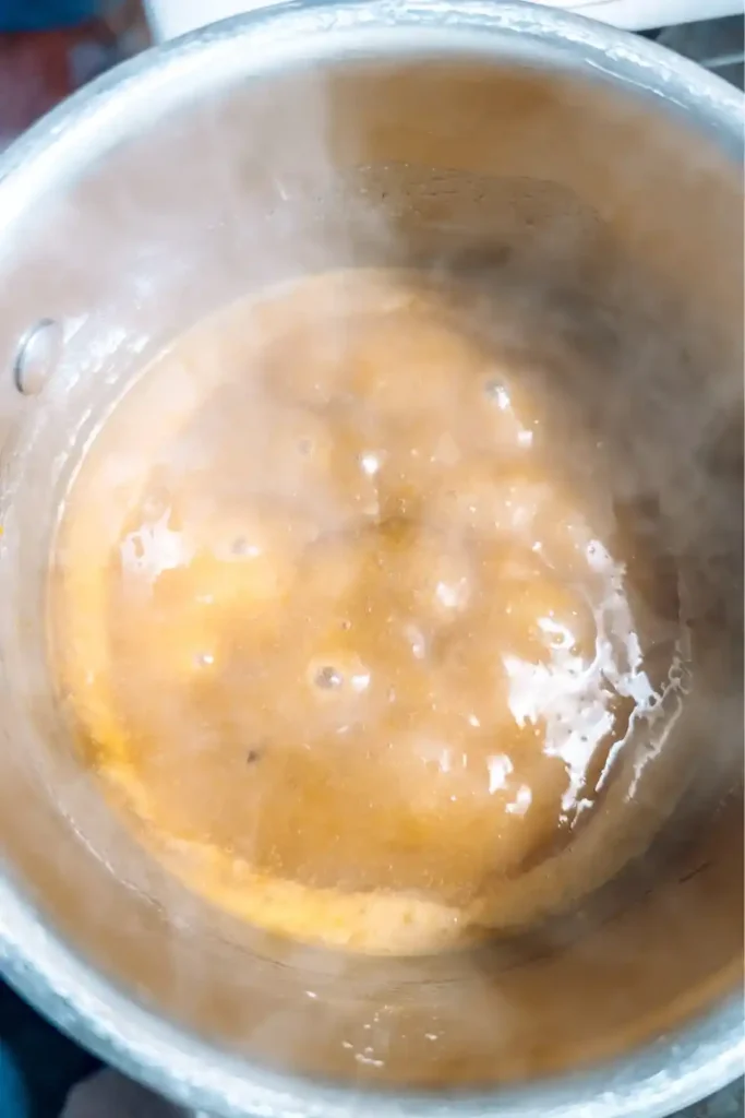 thickened boiling orange sauce in saucepan