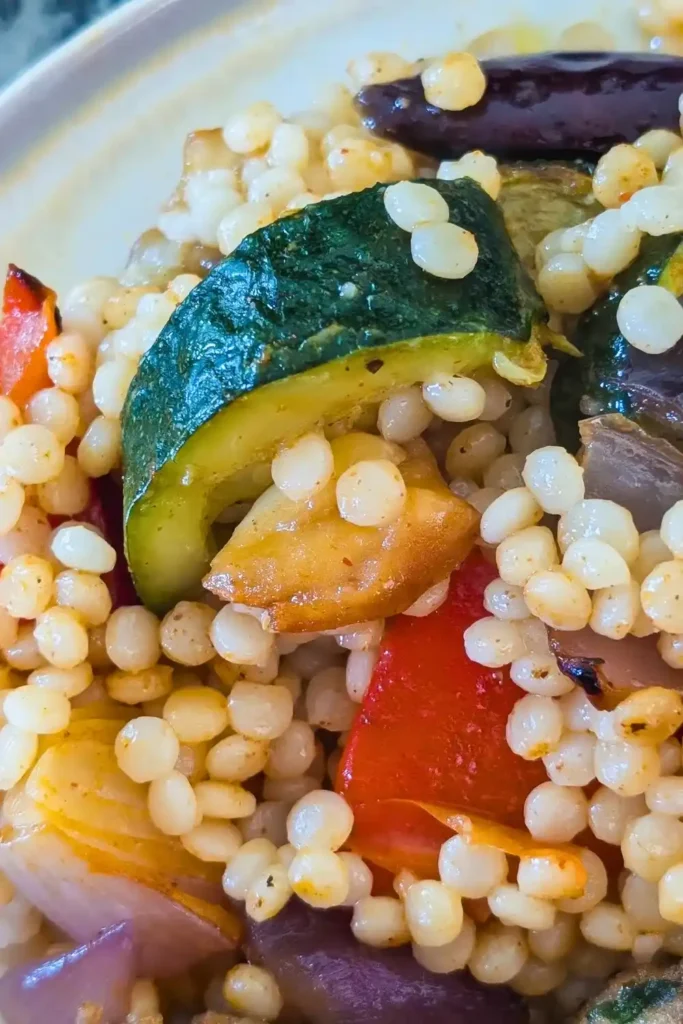 close up of couscous and veg on side of beige plate