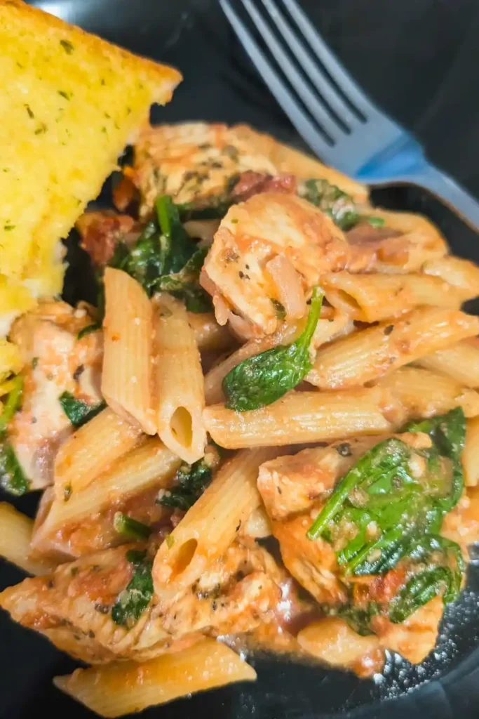 the penne pasta with rose sauce on plate with fork tines in upper right frame