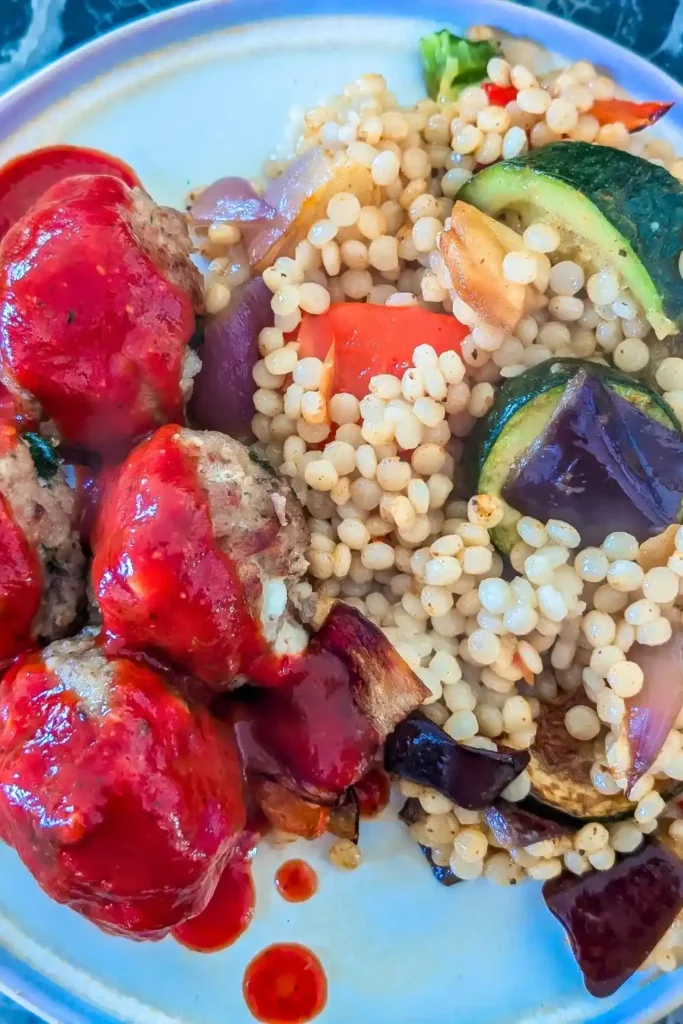 the couscous side dish with turkey meatballs on beige plate