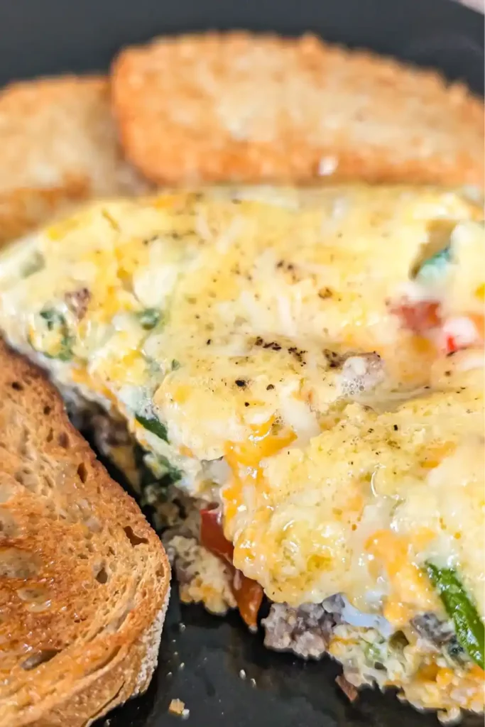 frittata on dark plate with hashbrowns and toast