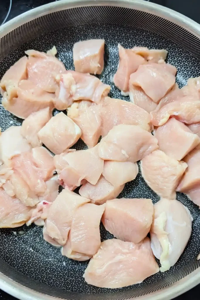 chicken breast pieces with olive oil in aluminum clad frying pan