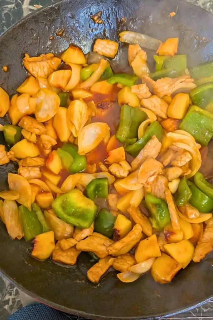 the sauced sweet and sour pork stir fry in the wok