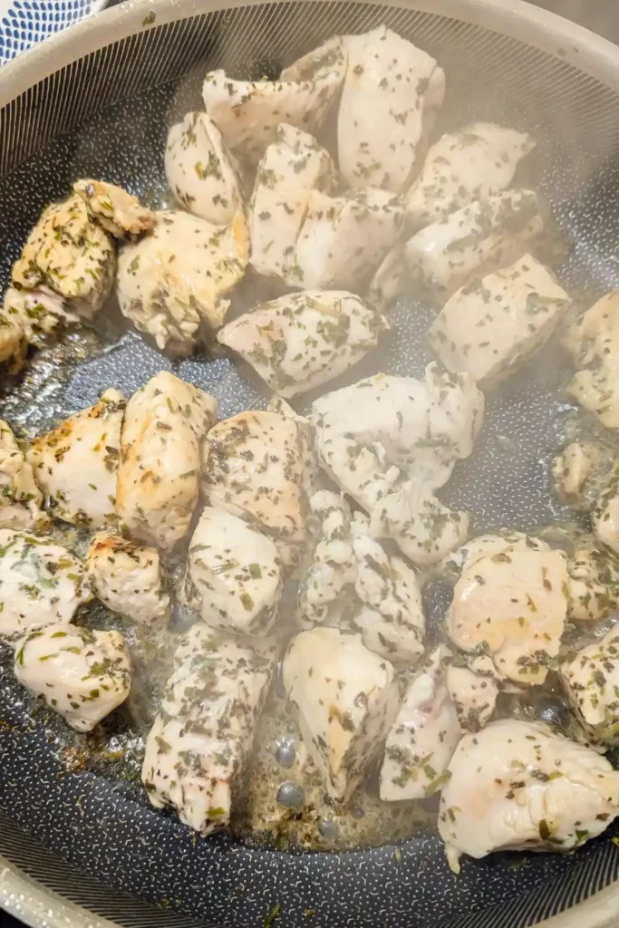 cooking the herbed chicken breast pieces in frying pan