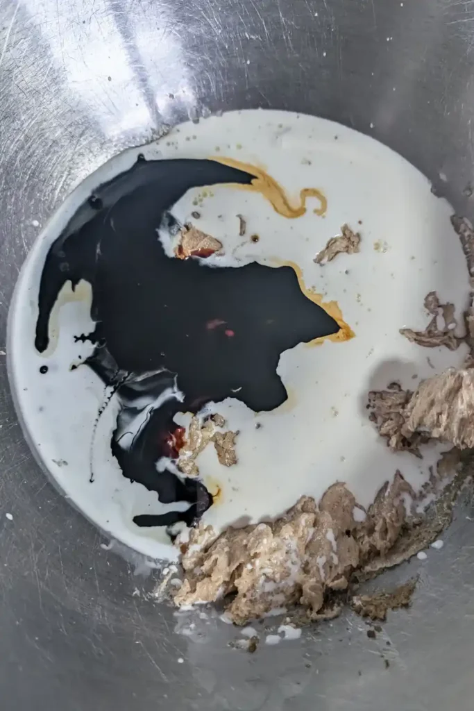 adding warm cream and molasses to creamed mixture in stainless steel mixing bowl