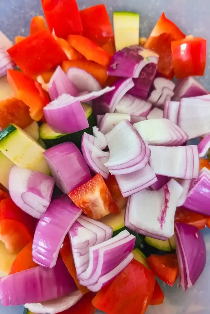 chopped red onion, red bell pepper and green zucchini in large bowl