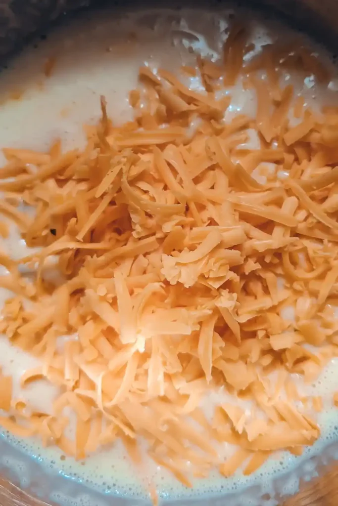 adding shredded cheddar cheese to the egg mixture
