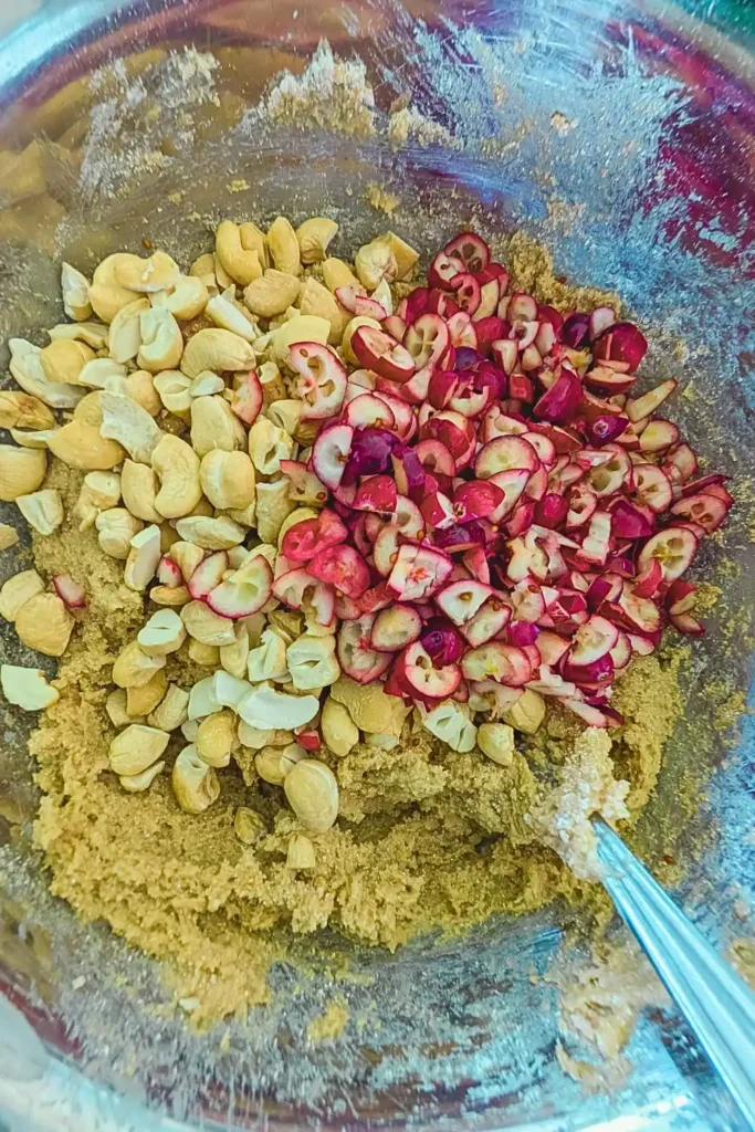 adding chopped fresh cranberries to cookie dough in mixing bowl