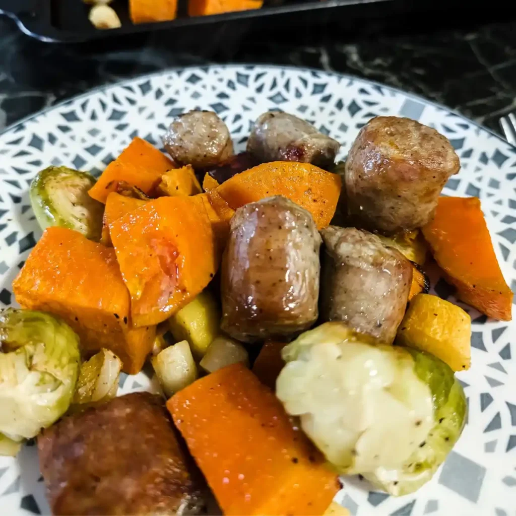recipe card image of serving of sausage with vegetables on blue and white plate