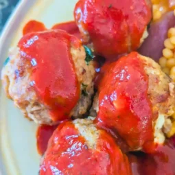 top down view of turkey meatballs with harissa sauce on beige plate edge showing