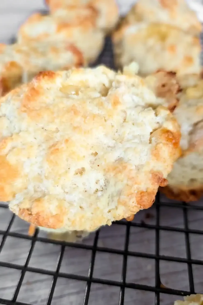 closeup top of a cheese biscuit with others in the background on wire baking rack