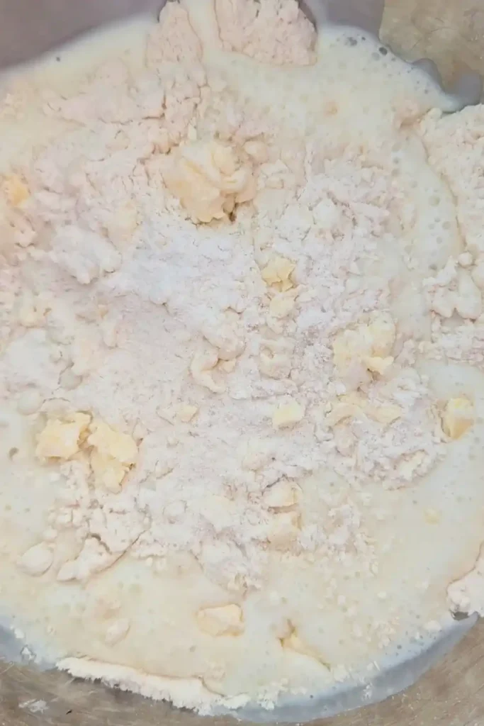 adding the buttermilk to the biscuit dough