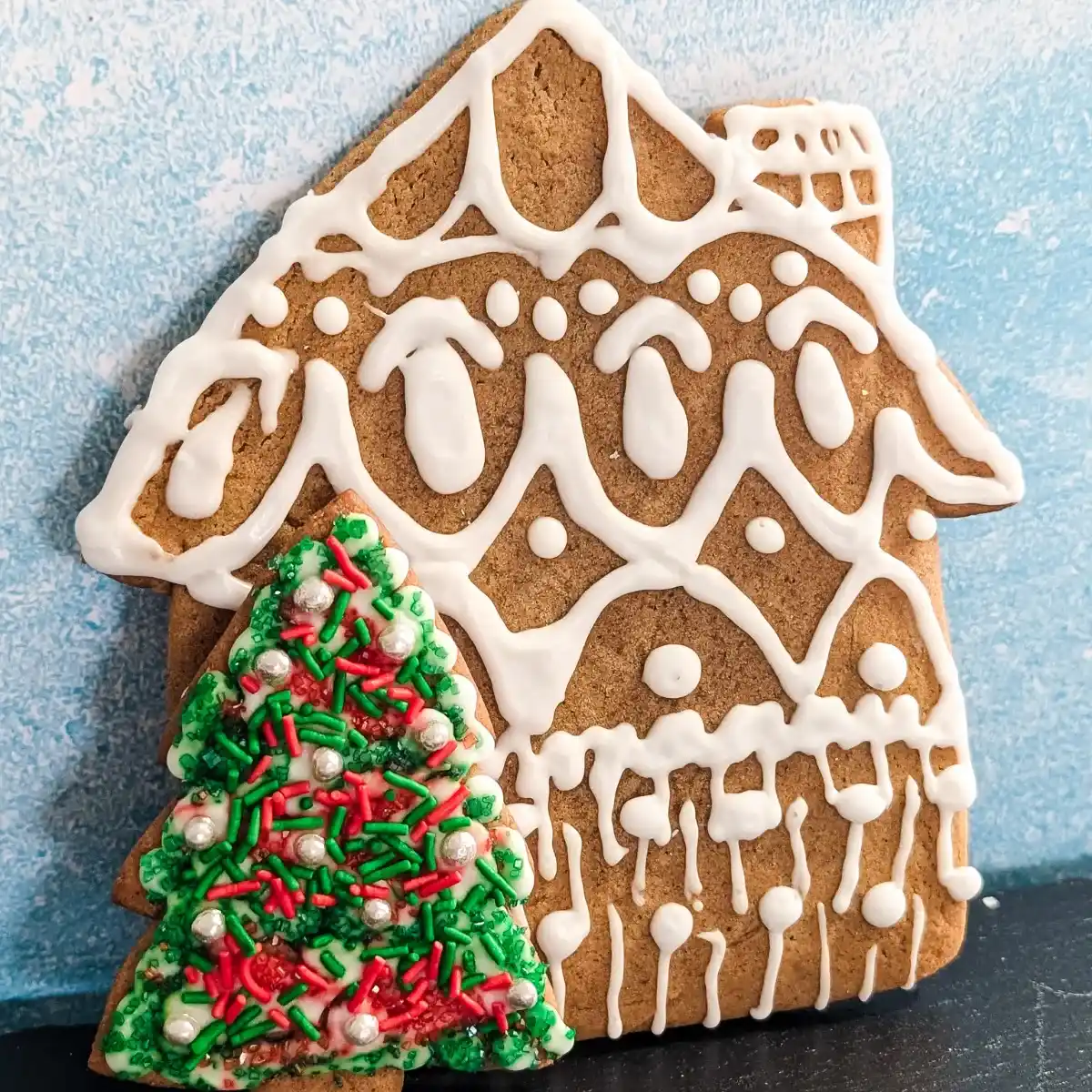 ornate white gingerbread house with candy decorated red and green tree