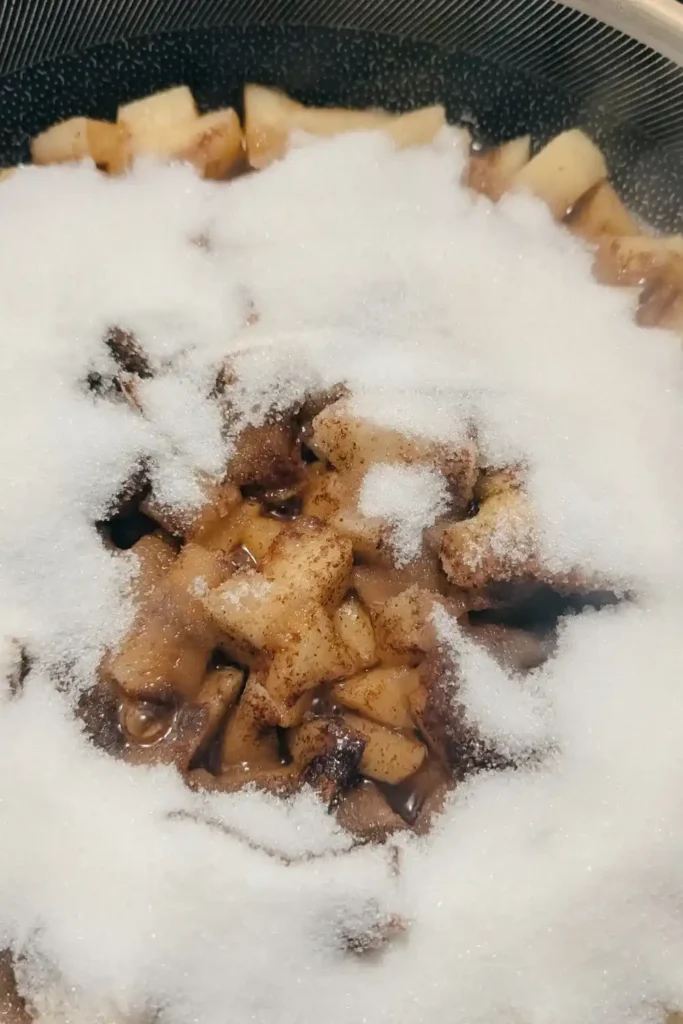 adding spices and sugar to apple in frying pan