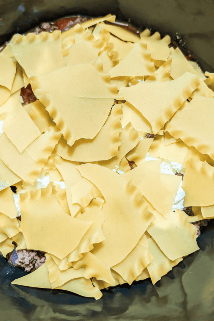 adding broken no boil lasagna noodles to dutch oven