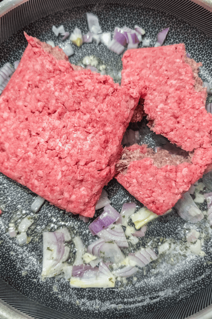 adding ground beef to sauteed onion and garlic