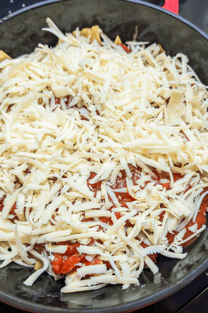 adding the shredded pizza mozzarella to dutch oven lasagna