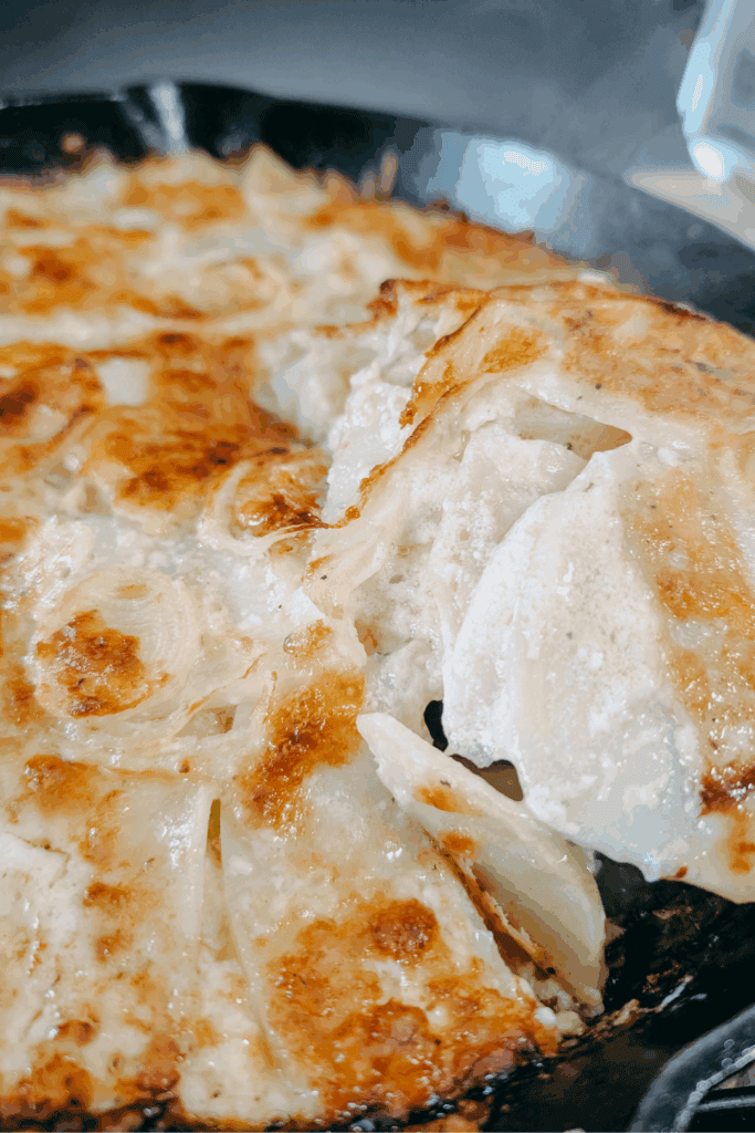 lifting cheesy potato gratin from pan