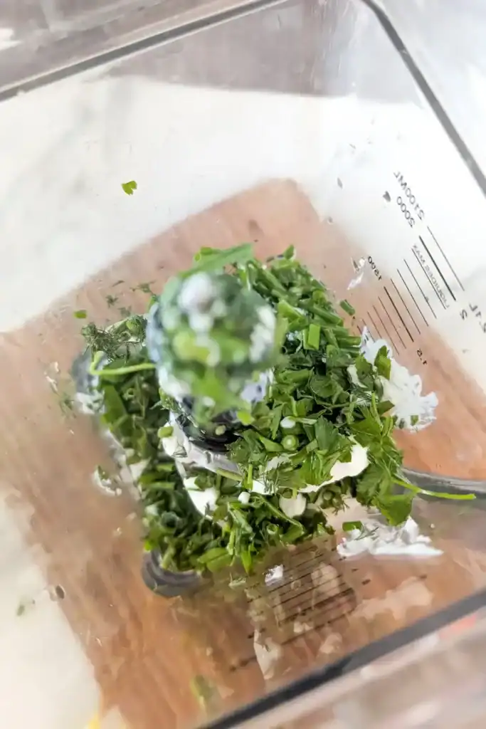 add olive oil and herbs to cottage cheese in blender a view down inside blender