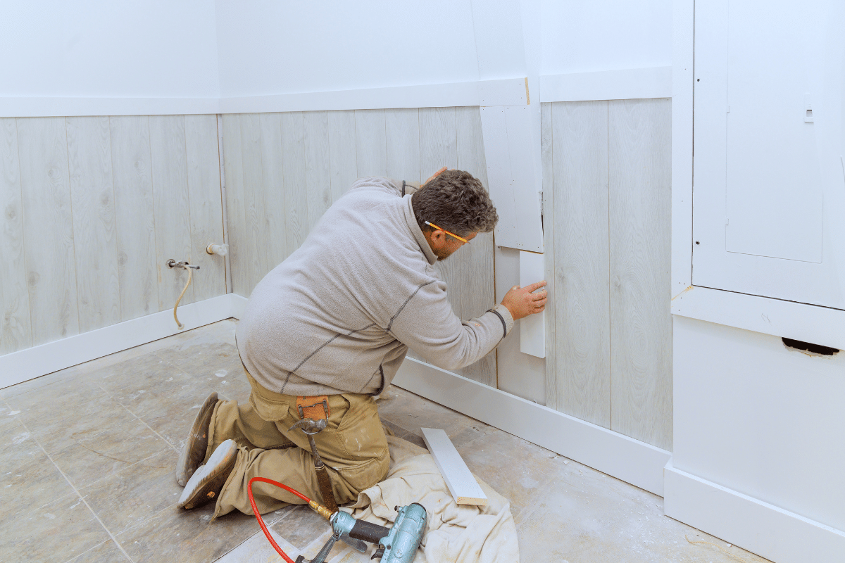 A Chupps Interior Construction worker installs wood paneling for a kitchen upgrade in a room being remodeled.