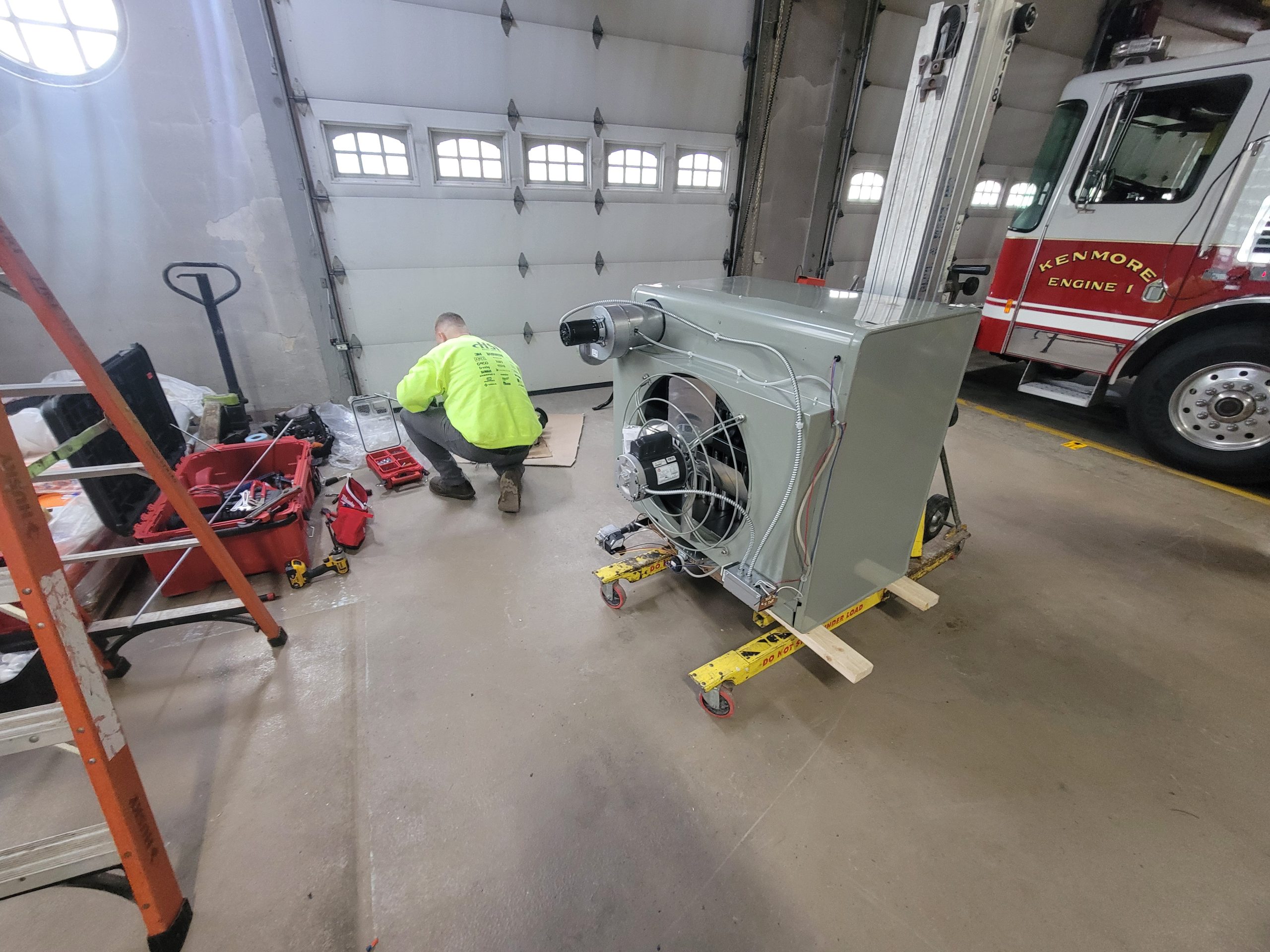 A worker from JP Heating & Cooling repairs a furnace in a garage, showing professional HVAC service for homes.