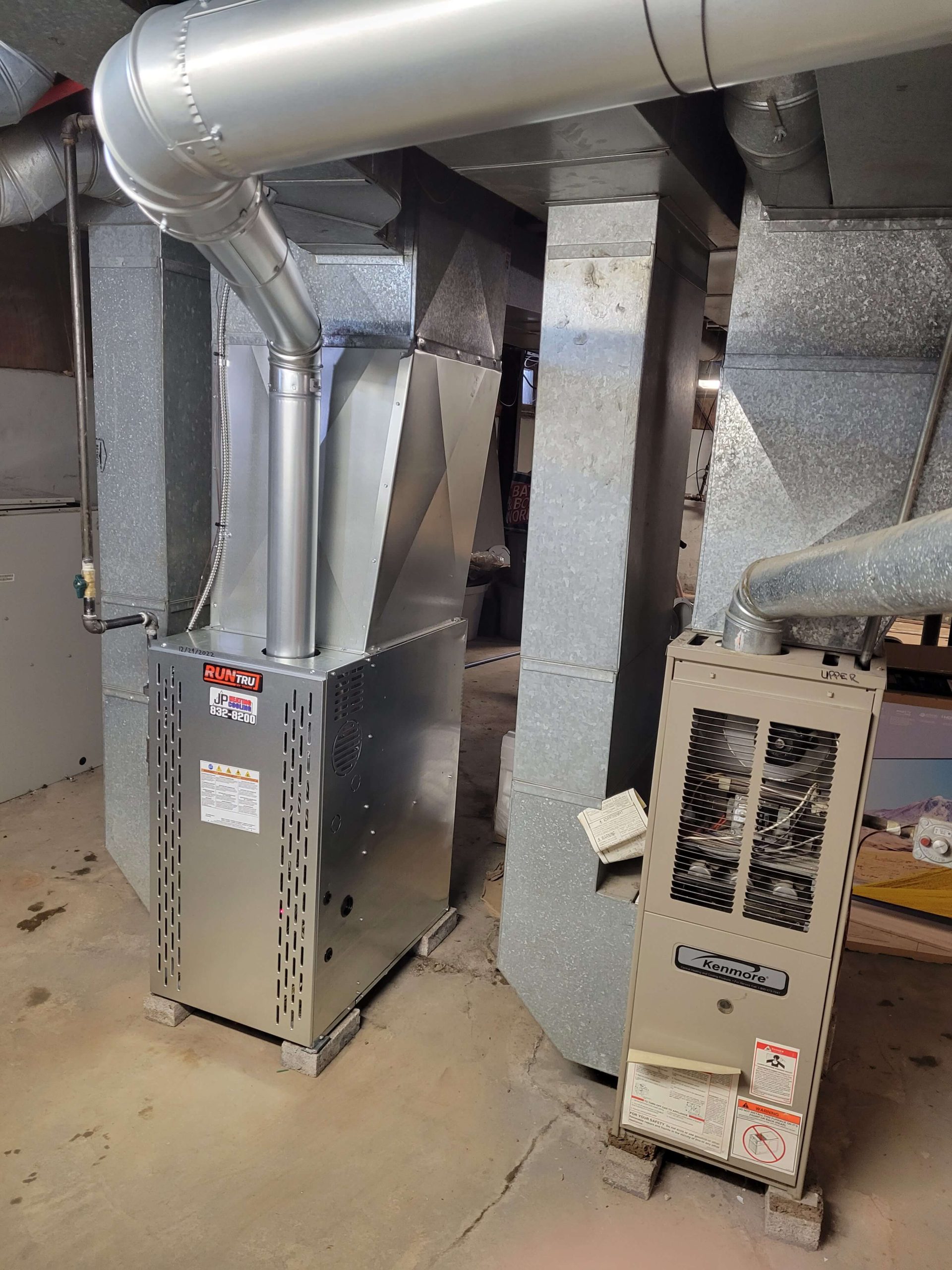 Two furnace units show the difference between new and old heating systems, highlighting JP Heating & Cooling’s repair services.