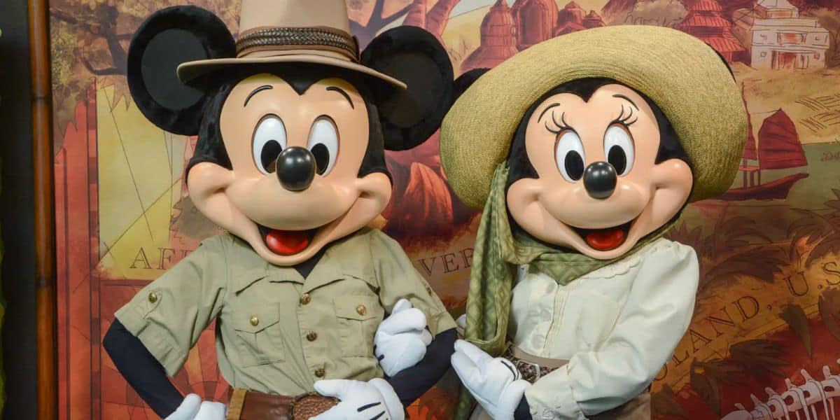 Two cartoon mice characters dressed in safari outfits. The one on the left wears a hat and khaki shirt, while the one on the right wears a large hat and scarf. They pose cheerfully against a themed backdrop.