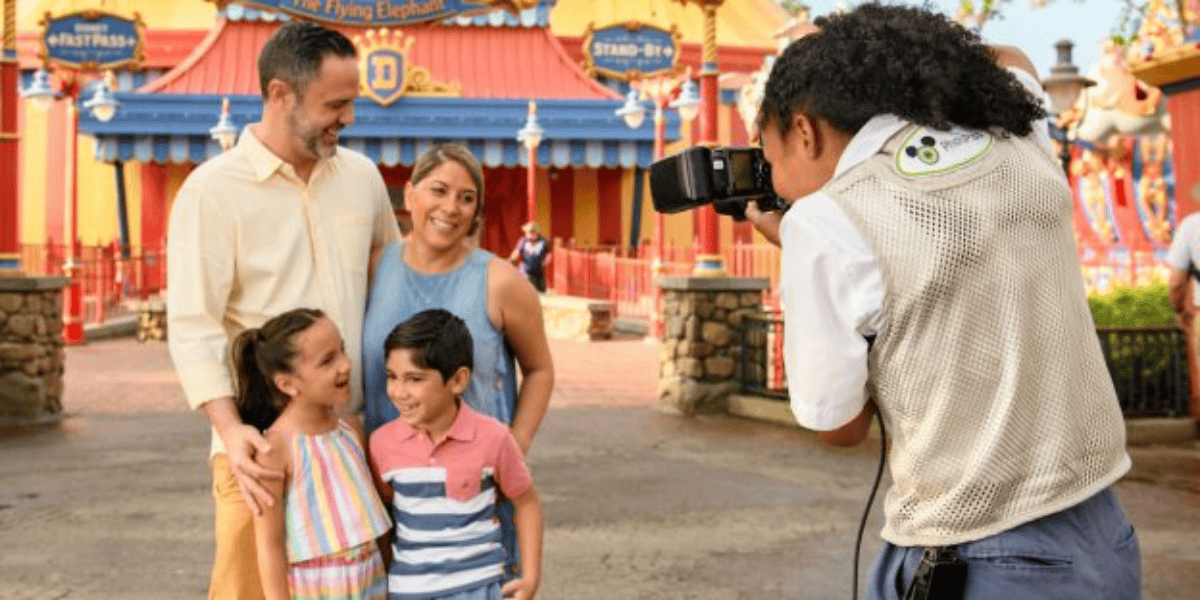 A family of four poses for a photo by a PhotoPass cast member at Disney World
