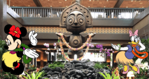 In a Polynesian Village-themed hotel lobby, a large wooden tiki statue adorned with flower garlands stands prominently. Cartoon characters, one with a red bow and another with a pink bow, pose on either side amid lush tropical plants, adding charm reminiscent of Disney Resorts' Magic Kingdom Area.