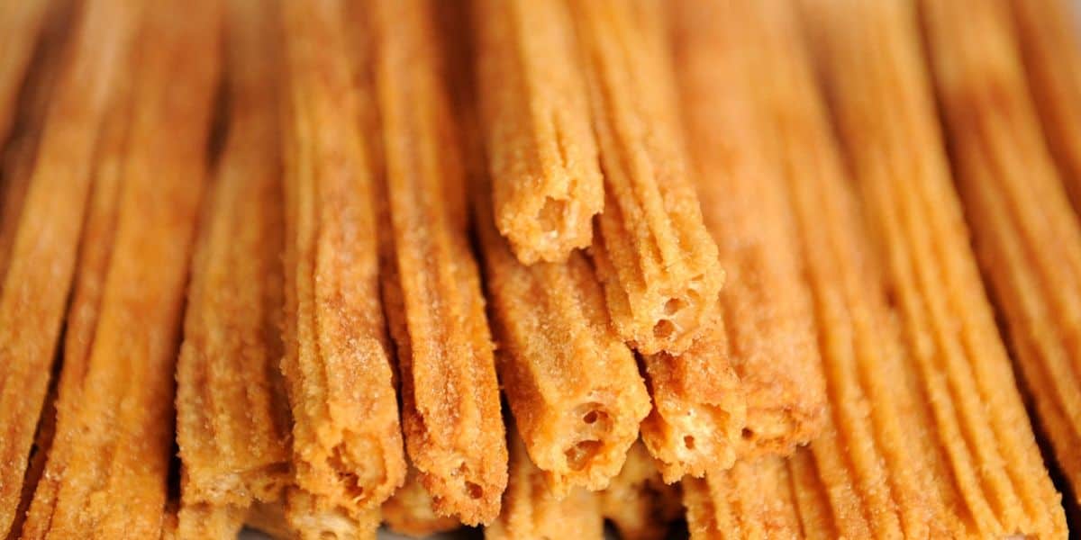 Close-up of several golden-brown churros stacked together, their crispy, textured exterior coated with sugar. These delightful treats evoke the magic of a Disney Christmas morning, each bite capturing the joy and wonder of the season.