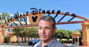 A man stands in front of the entrance archway to The Walt Disney Company, which features the Disney logo and a Mickey Mouse silhouette, with office buildings and trees in the background.