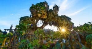 Fantasy landscape with floating mountains covered in lush greenery and vines, under a clear blue sky with sunlight streaming through. Exotic plants and pathways are visible below, creating an otherworldly atmosphere.