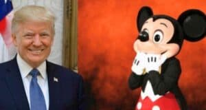 A man in a suit and tie, smiling with an American flag partially visible behind him on the left, is next to a large costumed character resembling Mickey Mouse, who has a surprised expression and is standing against an orange background on the right. This moment quickly caught the attention of news media outlets.