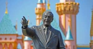 Walt Disney in front of disneyland castle