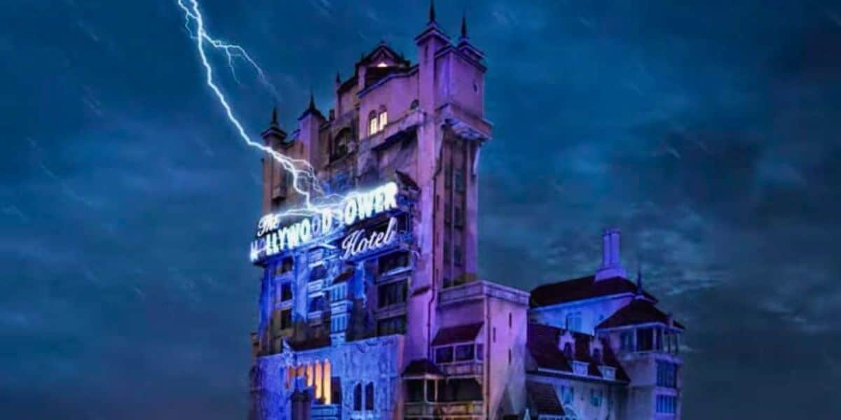 An image of the Tower of Terror, a gloomy, haunted-looking building, illuminated by a neon sign under a stormy sky with a lightning bolt striking.