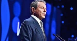 Bob Iger speaking at a podium against a blue-lit backdrop.