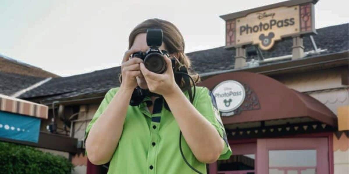 A Disney cast member taking a picture with a PhotoPass camera. 