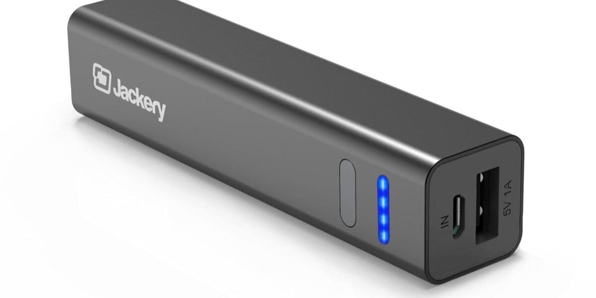 A black Jackery portable power bank with a rectangular, compact design, perfect for slipping into your carry-on bag for trips to Disney World. It features a USB-A port, a micro-USB input port, and a power button on one end. Four blue LED indicators show the remaining battery level. The Jackery logo is printed on the side.