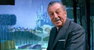 An older man in a suit stands smiling in front of a mural reminiscent of Disney World, depicting a fairytale landscape with a castle, trees, and an enchanting bridge. The background is colorful and illustrated in a whimsical style.