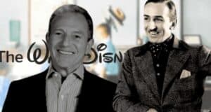 A grayscale photo of two smiling individuals standing in front of the Disney logo. One person is in a suit, and the other in a polka dot shirt with a jacket. The background is blurred, showing a hint of colorful artwork.