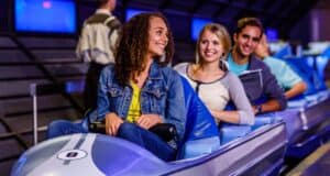 Three people sitting in a Space Mountain ride vehicle at Magic Kingdom Park