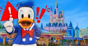 Donald Duck, wearing a blue sailor outfit and red bow tie, gestures with one hand raised in front of a colorful castle. Red exclamation marks and a warning triangle are overlaid on the image.